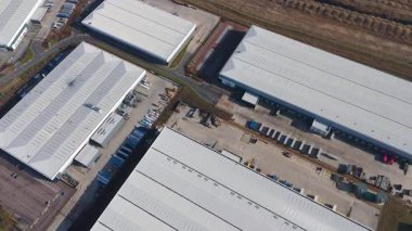 Büyük lojistik depoları ve dağıtım merkezleri, ağır yük kamyonları ve yükleme ambarları için hava aracı perspektifi, İngiltere