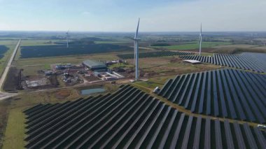 Büyük rüzgar türbini ve güneş paneli dizisinin hava aracı görüntüsü, yenilenebilir enerji santrali güneşli bahar sabahı Birleşik Krallık. Elektrik gücü..