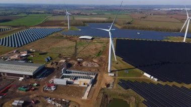 Büyük rüzgar türbini ve güneş paneli dizisinin hava aracı görüntüsü, yenilenebilir enerji santrali güneşli bahar sabahı Birleşik Krallık. Elektrik gücü..