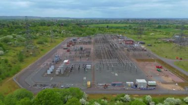 Elektrik hatları pilonları ve transformatörlerle elektrik şebekesine güç aktaran hava aracı görüntüsü.