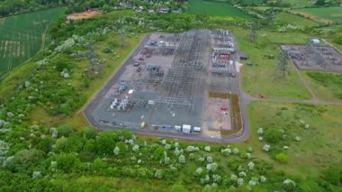 Elektrik hatları pilonları ve transformatörlerle elektrik şebekesine güç aktaran hava aracı görüntüsü.