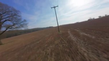 FPV insansız hava aracı gün batımında İngiltere 'nin yeşil arazilerinden geçer, çiftlik hayvanlarının, çitlerin ve çayırların yanından geçer, yukarıdan kırsal manzaranın güzelliğini yakalar.