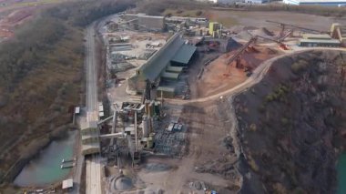Dev taş ocağı, açık çukur madeni, çakıl ve nadir bulunan toprak mineral çıkarma, taşıma bantları ve bitki makinelerinden oluşan hava aracı perspektifi.