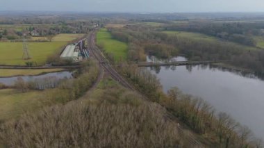 Büyük göl ve taş ocağının hava aracı görüntüsü. Köprü eski demiryolu hattını geçiyor, İngiltere ilkbaharında vahşi yaşam için sulak arazi.