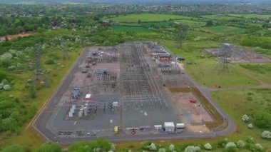 Elektrik hatları pilonları ve transformatörlerle elektrik şebekesine güç aktaran hava aracı görüntüsü.