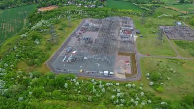 Elektrik hatları pilonları ve transformatörlerle elektrik şebekesine güç aktaran hava aracı görüntüsü.