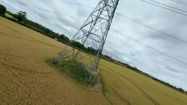 FPV insansız hava aracı, ekin ve buğday tarlaları üzerinde havadan görüş sağlıyor. Altın mısır tarlaları ve İngiltere kırsalındaki traktör ve elektrik hatları için pist işaretleri.