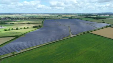 Büyük güneş paneli kurulumunun hava aracı görüntüsü. İngiliz kırsalındaki yenilenebilir kaynaklardan fotovoltaik elektrik santralleri. Güneşli bir yaz günü Birleşik Krallık.