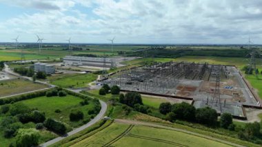 Keadby enerji santralinin hava aracı görüntüsü, pilonları ve kabloları olan elektrik alt istasyonu, yenilenebilir enerji kaynakları için rüzgar türbinleri. Yeşil kritik sanayi altyapısı, Keadby, Birleşik Krallık.