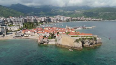 Budva 'nın eski kenti, Stari mezunu, terracotta çatısı ve şehir, dağ arkaplanı ve Karadağ' ın Avrupa manzarasının insansız hava aracı görüntüsü.
