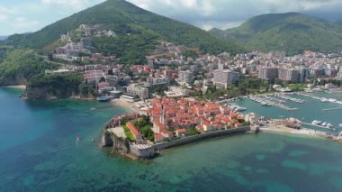 Budva 'nın eski kenti, Stari mezunu, terracotta çatısı ve şehir, dağ arkaplanı ve Karadağ' ın Avrupa manzarasının insansız hava aracı görüntüsü.
