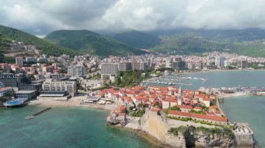 Budva 'nın eski kenti, Stari mezunu, terracotta çatısı ve şehir, dağ arkaplanı ve Karadağ' ın Avrupa manzarasının insansız hava aracı görüntüsü.
