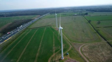 İngiltere 'de M1' de geniş rüzgar türbini dizisi ve yoğun otoyol trafiğinin hava aracı görüntüsü. Sürdürülebilir yenilenebilir enerji ve ulaşım temaları.