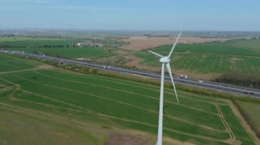 İngiltere 'de M1' de geniş rüzgar türbini dizisi ve yoğun otoyol trafiğinin hava aracı görüntüsü. Sürdürülebilir yenilenebilir enerji ve ulaşım temaları.