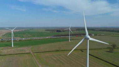 İngiltere 'de M1' de geniş rüzgar türbini dizisi ve yoğun otoyol trafiğinin hava aracı görüntüsü. Sürdürülebilir yenilenebilir enerji ve ulaşım temaları.