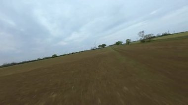 FPV insansız hava aracı görüntüsü, İngiltere 'deki rüzgar türbinleri ve kırsal alanlar üzerinden alçak geçiş yapıyor.