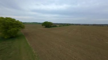 FPV insansız hava aracı görüntüsü, İngiltere 'deki rüzgar türbinleri ve kırsal alanlar üzerinden alçak geçiş yapıyor.