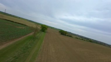 FPV insansız hava aracı görüntüsü, İngiltere 'deki rüzgar türbinleri ve kırsal alanlar üzerinden alçak geçiş yapıyor.