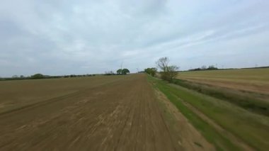 FPV insansız hava aracı görüntüsü, İngiltere 'deki rüzgar türbinleri ve kırsal alanlar üzerinden alçak geçiş yapıyor.