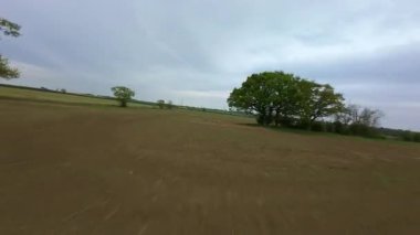 FPV insansız hava aracı görüntüsü, İngiltere 'deki rüzgar türbinleri ve kırsal alanlar üzerinden alçak geçiş yapıyor.