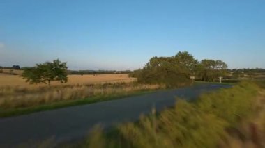 FPV hava görüntüsü, İngiltere 'de kırsal alanlar ve araziler, tarım ve çiftlik hayvanları üzerinde hızlı bir şekilde uçuşa geçiyor.