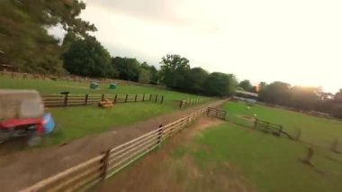 FPV hava görüntüsü, İngiltere 'de kırsal alanlar ve araziler, tarım ve çiftlik hayvanları üzerinde hızlı bir şekilde uçuşa geçiyor.