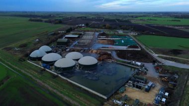 Modern bir yenilenebilir enerji biyogaz santralinin insansız hava aracı görüntüsü tarım atıklarını İngiltere kırsalında yeşil elektriğe dönüştürüyor..