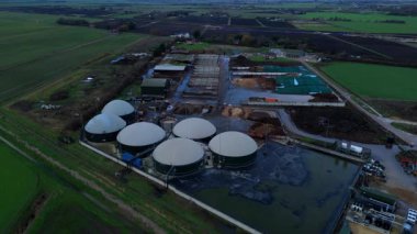 Modern bir yenilenebilir enerji biyogaz santralinin insansız hava aracı görüntüsü tarım atıklarını İngiltere kırsalında yeşil elektriğe dönüştürüyor..