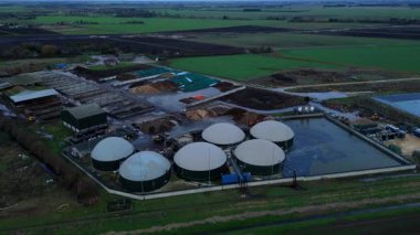Modern bir yenilenebilir enerji biyogaz santralinin insansız hava aracı görüntüsü tarım atıklarını İngiltere kırsalında yeşil elektriğe dönüştürüyor..