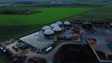 Modern bir yenilenebilir enerji biyogaz santralinin insansız hava aracı görüntüsü tarım atıklarını İngiltere kırsalında yeşil elektriğe dönüştürüyor..