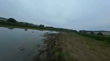 FPV insansız hava aracı Rutland İngiltere 'de yemyeşil sulak arazi ve Göz Brooke rezervuarı bulutlu bulutlu gün üzerinden geçiyor.