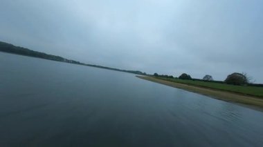 FPV insansız hava aracı Rutland İngiltere 'de yemyeşil sulak arazi ve Göz Brooke rezervuarı bulutlu bulutlu gün üzerinden geçiyor.