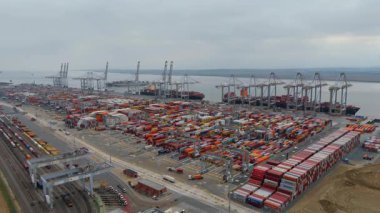 Bir sürü yük konteynırı ve büyük kargo gemisi kenetlenmiş büyük bir nakliye limanının insansız hava aracı görüntüsü, Gri trenler ve ithalat için malları taşıyan HGV 'ler, Londra Thames UK kapısı.