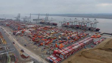 Bir sürü yük konteynırı ve büyük kargo gemisi kenetlenmiş büyük bir nakliye limanının insansız hava aracı görüntüsü, Gri trenler ve ithalat için malları taşıyan HGV 'ler, Londra Thames UK kapısı.