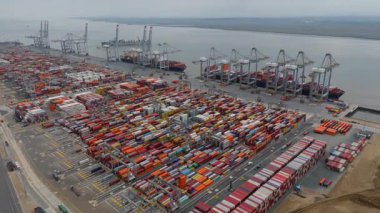 Bir sürü yük konteynırı ve büyük kargo gemisi kenetlenmiş büyük bir nakliye limanının insansız hava aracı görüntüsü, Gri trenler ve ithalat için malları taşıyan HGV 'ler, Londra Thames UK kapısı.