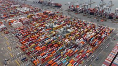 Bir sürü yük konteynırı ve büyük kargo gemisi kenetlenmiş büyük bir nakliye limanının insansız hava aracı görüntüsü, Gri trenler ve ithalat için malları taşıyan HGV 'ler, Londra Thames UK kapısı.