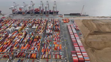 Bir sürü yük konteynırı ve büyük kargo gemisi kenetlenmiş büyük bir nakliye limanının insansız hava aracı görüntüsü, Gri trenler ve ithalat için malları taşıyan HGV 'ler, Londra Thames UK kapısı.