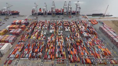 Bir sürü yük konteynırı ve büyük kargo gemisi kenetlenmiş büyük bir nakliye limanının insansız hava aracı görüntüsü, Gri trenler ve ithalat için malları taşıyan HGV 'ler, Londra Thames UK kapısı.