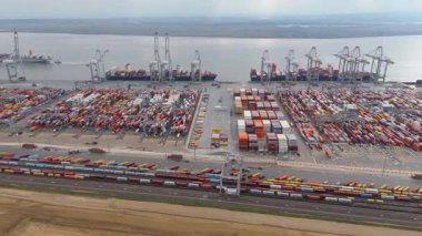 Bir sürü yük konteynırı ve büyük kargo gemisi kenetlenmiş büyük bir nakliye limanının insansız hava aracı görüntüsü, Gri trenler ve ithalat için malları taşıyan HGV 'ler, Londra Thames UK kapısı.