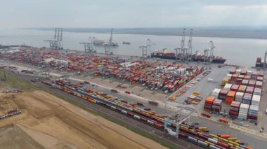 Bir sürü yük konteynırı ve büyük kargo gemisi kenetlenmiş büyük bir nakliye limanının insansız hava aracı görüntüsü, Gri trenler ve ithalat için malları taşıyan HGV 'ler, Londra Thames UK kapısı.