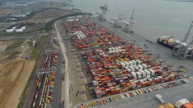 Bir sürü yük konteynırı ve büyük kargo gemisi kenetlenmiş büyük bir nakliye limanının insansız hava aracı görüntüsü, Gri trenler ve ithalat için malları taşıyan HGV 'ler, Londra Thames UK kapısı.