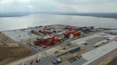 Bir sürü yük konteynırı ve büyük kargo gemisi kenetlenmiş büyük bir nakliye limanının insansız hava aracı görüntüsü, Gri trenler ve ithalat için malları taşıyan HGV 'ler, Londra Thames UK kapısı.