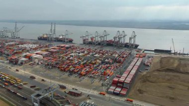 Bir sürü yük konteynırı ve büyük kargo gemisi kenetlenmiş büyük bir nakliye limanının insansız hava aracı görüntüsü, Gri trenler ve ithalat için malları taşıyan HGV 'ler, Londra Thames UK kapısı.