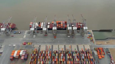 Bir sürü yük konteynırı ve büyük kargo gemisi kenetlenmiş büyük bir nakliye limanının insansız hava aracı görüntüsü, Gri trenler ve ithalat için malları taşıyan HGV 'ler, Londra Thames UK kapısı.
