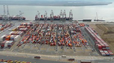 Bir sürü yük konteynırı ve büyük kargo gemisi kenetlenmiş büyük bir nakliye limanının insansız hava aracı görüntüsü, Gri trenler ve ithalat için malları taşıyan HGV 'ler, Londra Thames UK kapısı.