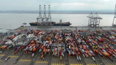 Bir sürü yük konteynırı ve büyük kargo gemisi kenetlenmiş büyük bir nakliye limanının insansız hava aracı görüntüsü, Gri trenler ve ithalat için malları taşıyan HGV 'ler, Londra Thames UK kapısı.