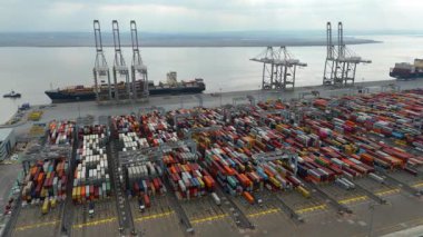 Bir sürü yük konteynırı ve büyük kargo gemisi kenetlenmiş büyük bir nakliye limanının insansız hava aracı görüntüsü, Gri trenler ve ithalat için malları taşıyan HGV 'ler, Londra Thames UK kapısı.
