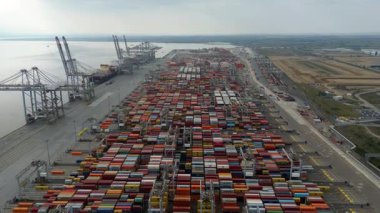 Bir sürü yük konteynırı ve büyük kargo gemisi kenetlenmiş büyük bir nakliye limanının insansız hava aracı görüntüsü, Gri trenler ve ithalat için malları taşıyan HGV 'ler, Londra Thames UK kapısı.