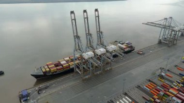 Bir sürü yük konteynırı ve büyük kargo gemisi kenetlenmiş büyük bir nakliye limanının insansız hava aracı görüntüsü, Gri trenler ve ithalat için malları taşıyan HGV 'ler, Londra Thames UK kapısı.