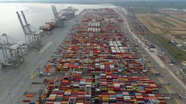 Bir sürü yük konteynırı ve büyük kargo gemisi kenetlenmiş büyük bir nakliye limanının insansız hava aracı görüntüsü, Gri trenler ve ithalat için malları taşıyan HGV 'ler, Londra Thames UK kapısı.